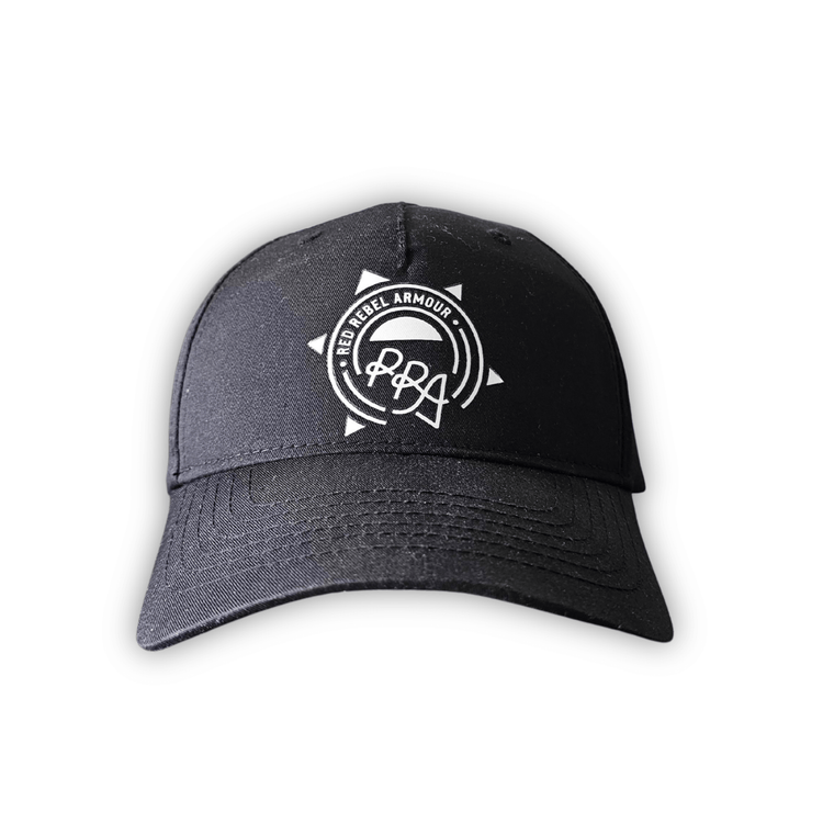 Black snapback hat with white printed Red Rebel Armour crest on front panel, displayed on a wooden table.